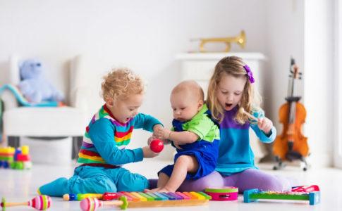 musikalische Früherziehung sinnvoll? - drei Kinder spielen mit Kindermusikinstrumenten