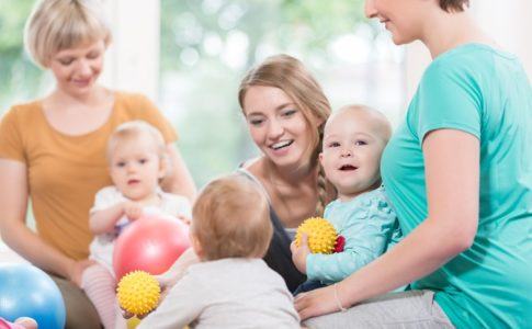 drei kinder spielen mit vier jungen Frauen im sitzen