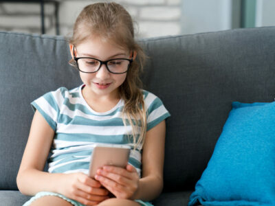 Ein junges Mädchen blickt interessiert auf ein Smartphone