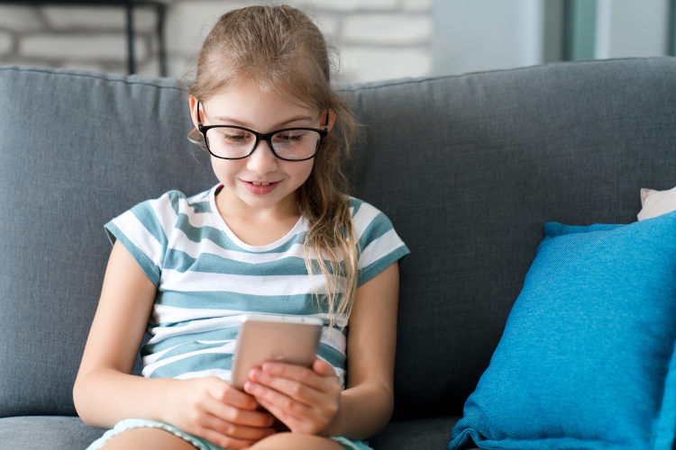 Ein junges Mädchen blickt interessiert auf ein Smartphone