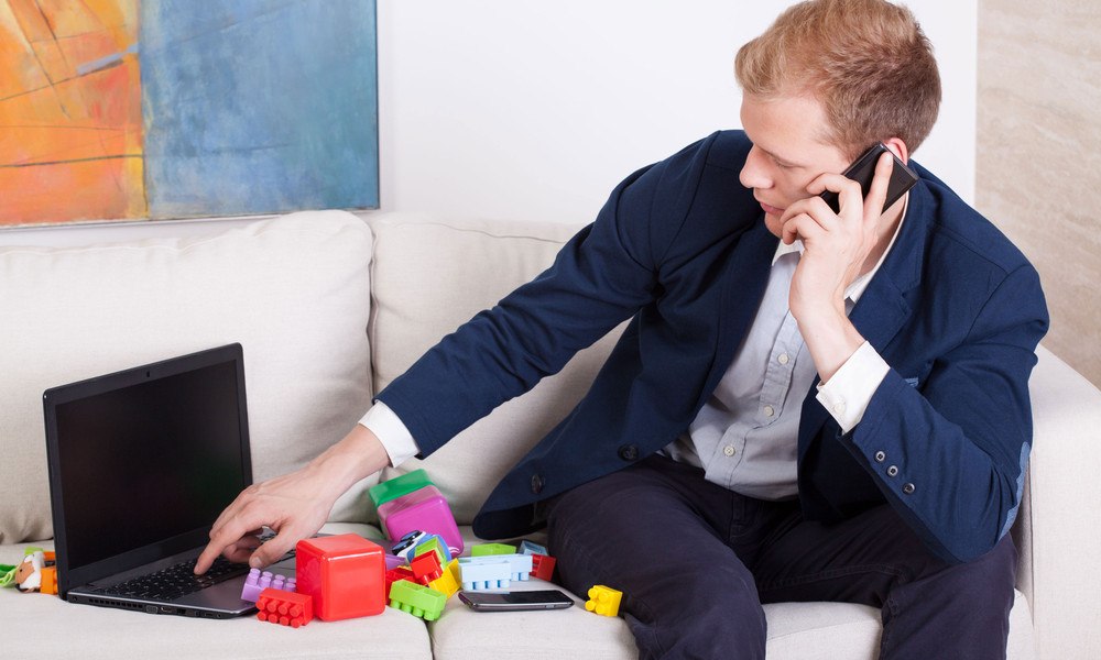 Geschäftsmann sitzt mit Laptop zwischen Spielzeug