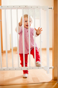 Kleinkind steht vor Absperrung der Treppe