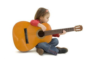 Mädchen sitzt mit Gitarre auf Boden