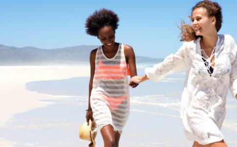 sommerliche mode - zwei Frauen laufen am Strand in Sommerkleidern