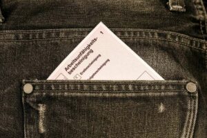 Eine Arbeitsunfähigkeitsbescheinigung steckt in der hinteren Tasche einer Hose