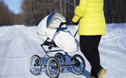 Mutter mit Kinderwagen im Schnee